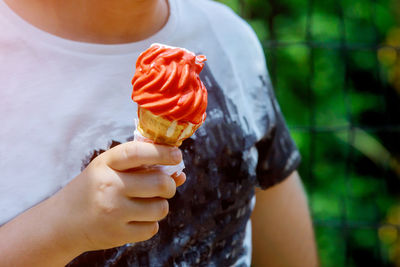 Close-up of boy holding red ice cream outdoors