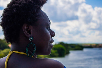 Portrait of young woman looking away against sky