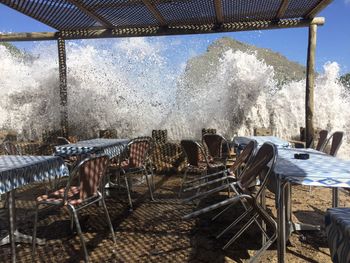 Empty chairs and tables by sea