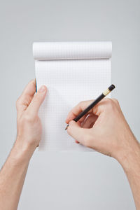 Close-up of hand holding book against white background