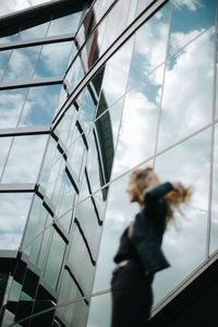 Low angle view of people walking on glass window