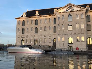 Boats in canal by buildings against sky