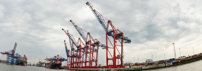 Cranes at commercial dock against sky