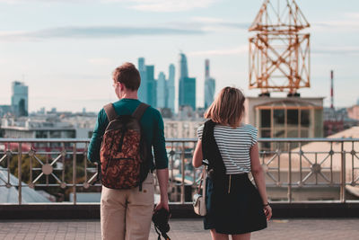 Rear view of man and woman standing against cityscape