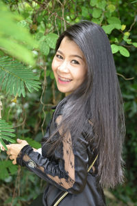 Portrait of smiling woman standing against plants