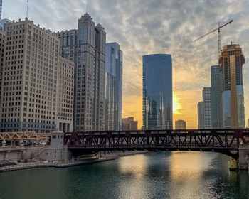 Bridge over river by buildings against sky in city