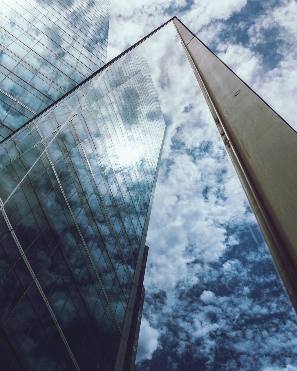 architecture, low angle view, built structure, building exterior, glass - material, sky, cloud - sky, window, reflection, cloudy, city, modern, glass, cloud, transparent, office building, building, day, skyscraper, tall - high