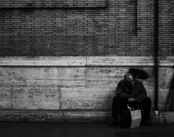 Full length of couple sitting on brick wall