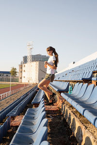 Young woman standing on built structure against clear sky