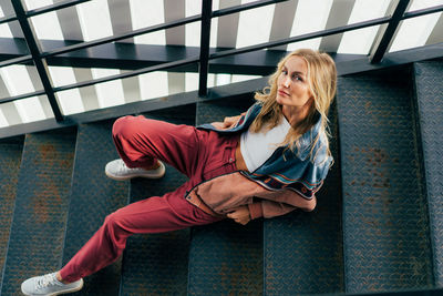 Cheeky modern woman looking at camera while sitting on steps person