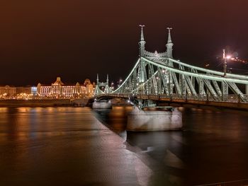 Illuminated bridge over river at night