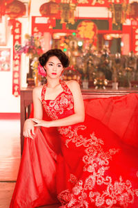 Young woman in red dress sitting on sofa at home