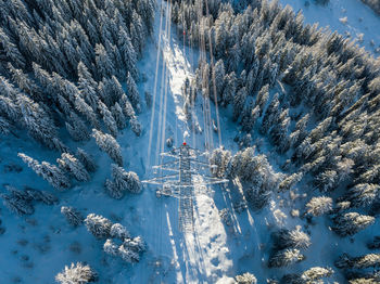 Directly above shot electrical pylon on snow covered land