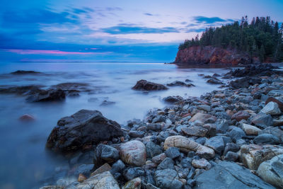 Rocks by sea against sky