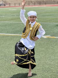 Rear view of man with arms raised standing on field