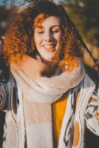 Portrait of smiling young woman standing against tree trunk