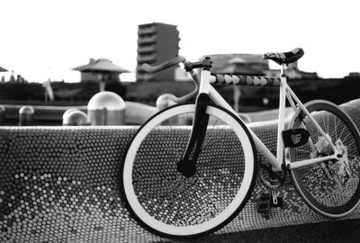 Bicycle parked by retaining wall against clear sky