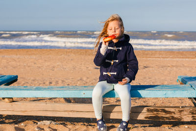 Girl in delight eats donut with red icing, food stained her mouth