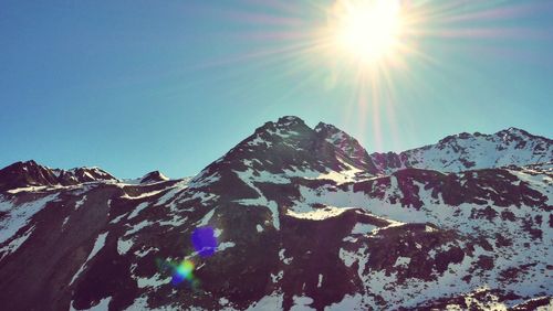 Scenic view of snowcapped mountains during sunny day