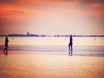 Silhouette of people on beach at sunset