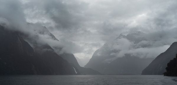 Scenic view of sea and mountains against storm clouds