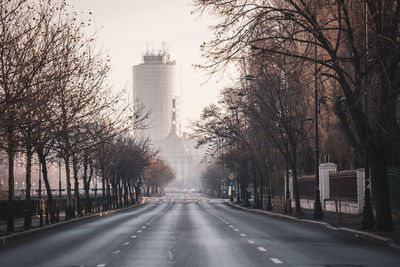 Road amidst trees against sky in city