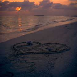 Close-up of beach against sky during sunset