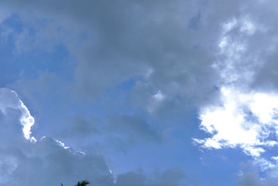 Low angle view of sunlight streaming through clouds