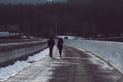 Rear view of friends walking on snow covered road