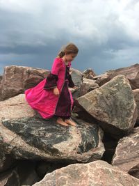 Rear view of woman on rock against sky