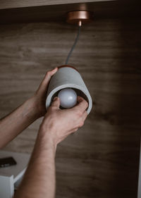 Cropped hands adjusting pendant light in home