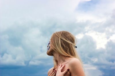 Young woman against cloudy sky