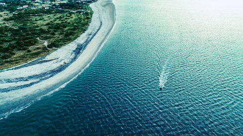 Aerial photo of a fishing boat close to a sandy beach with palm trees 