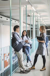 Male and female students talking while standing in corridor of university