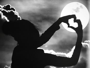 Close-up portrait of silhouette man holding woman against sky