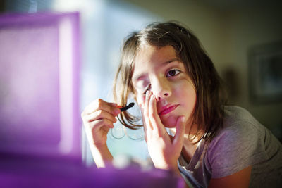 Close-up of girl applying makeup at home