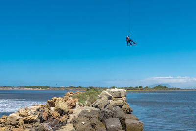 Man kiteboarding over sea against clear blue sky