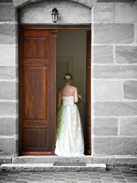 Rear view of bride standing on door