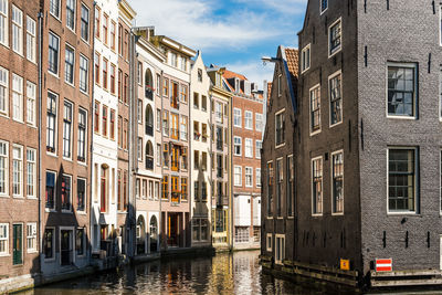 Canal amidst buildings in city against sky