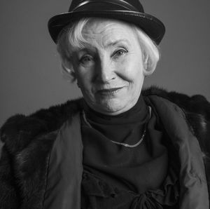 Close-up portrait of confident senior woman against gray background