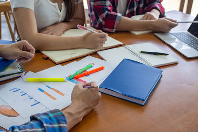 Midsection of man reading book on table