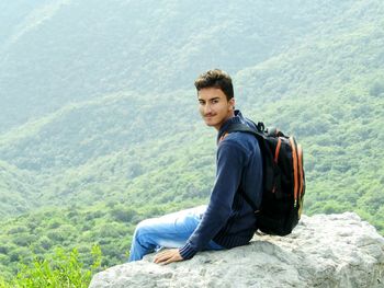 Portrait of man sitting on rock at margalla hills