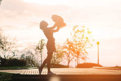 Full length of woman standing on beach against sky during sunset