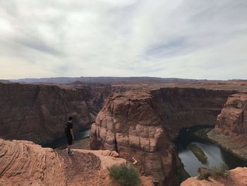 Man standing on rock formation against sky