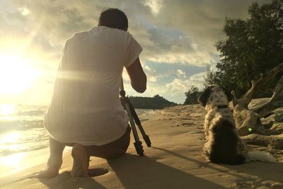 Rear view of man photographing on beach against sky