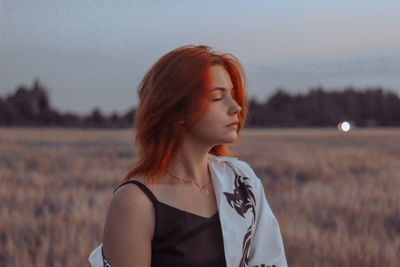 Portrait of woman standing on field against sky