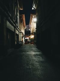 Walkway in illuminated city at night