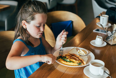 Midsection of woman holding food while sitting on table