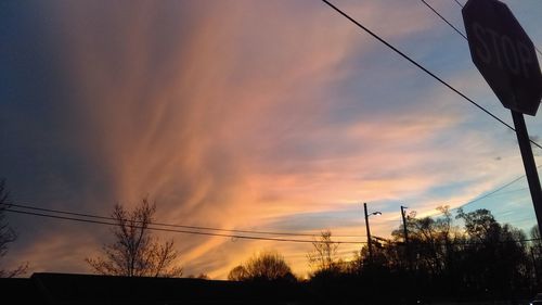 Low angle view of electricity pylon against cloudy sky