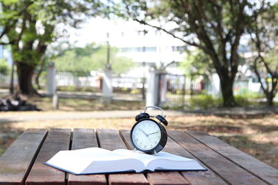 Close-up of clock with open book on table